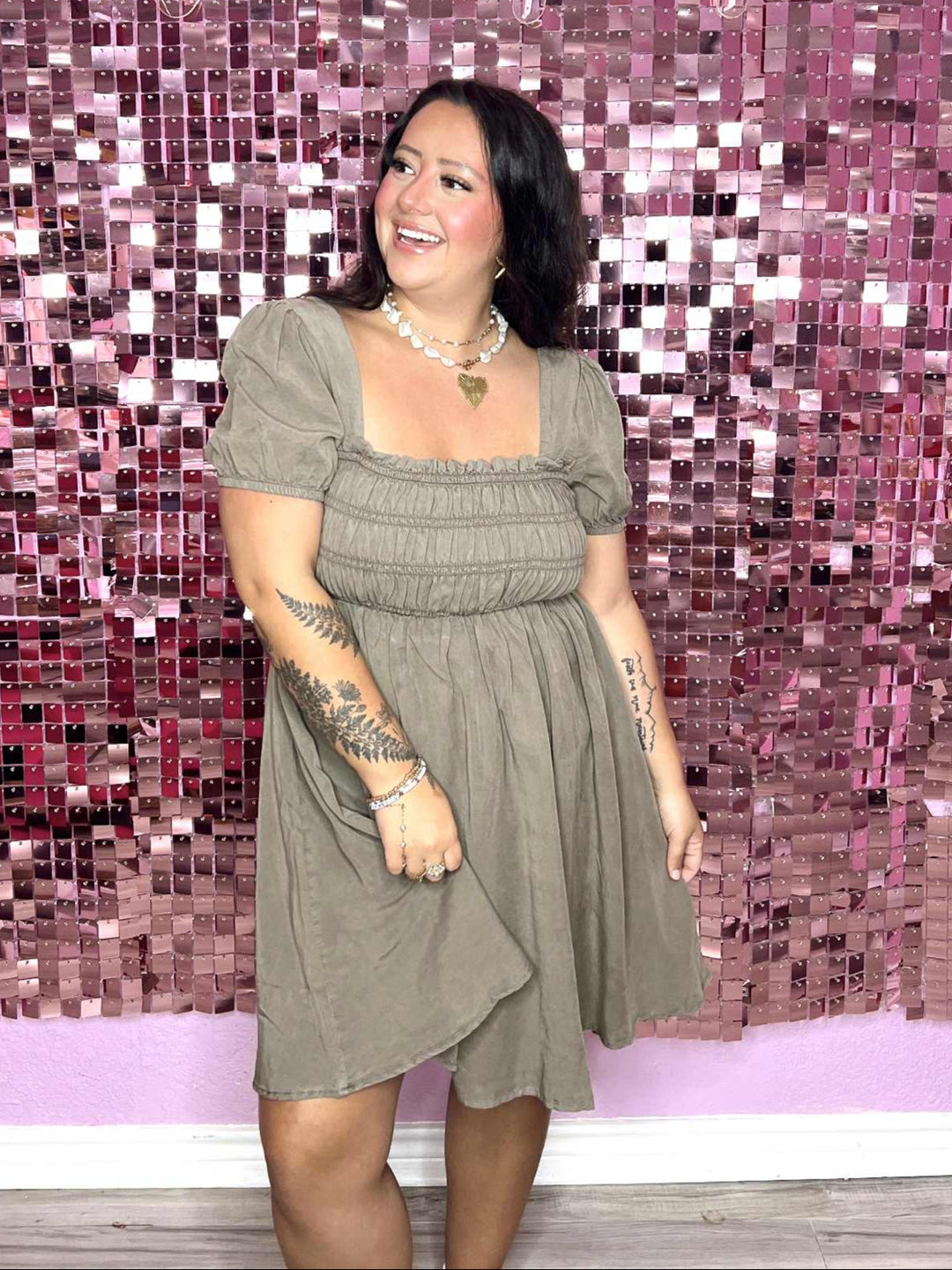 Woman in a green dress standing in front of a pink mosaic wall with 'Pug on a Pontoon' text.