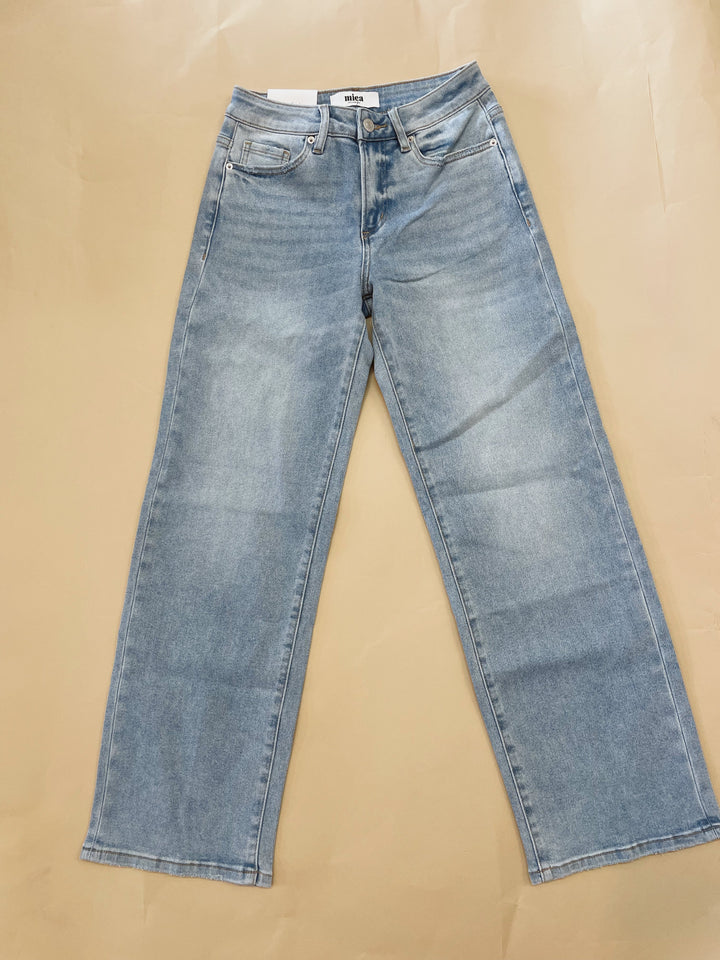 Pair of blue jeans laid flat on a beige surface
